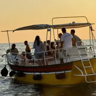 Group of tourists enjoying a sunset dolphin watching tour on a boat in Rovinj, Croatia.