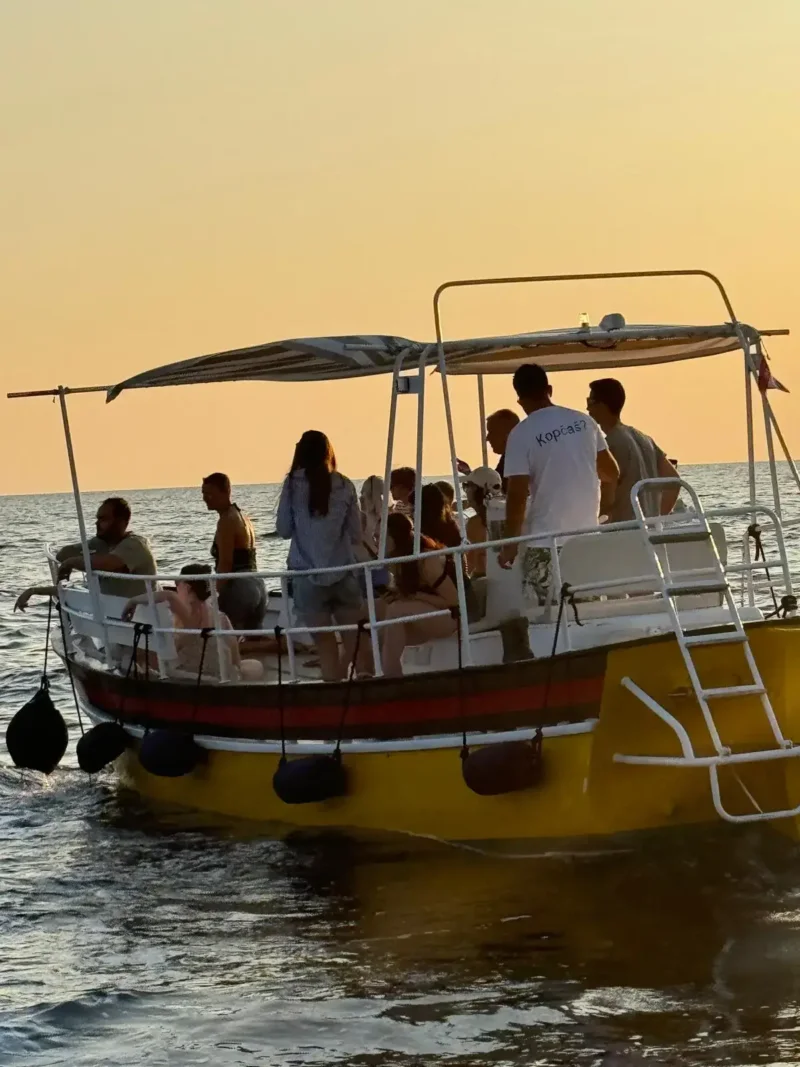 Group of tourists enjoying a sunset dolphin watching tour on a boat in Rovinj, Croatia.