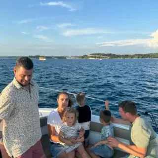 Family enjoying the sea breeze on a boat during the Family Dolphin Watching Tour in Rovinj, Croatia.